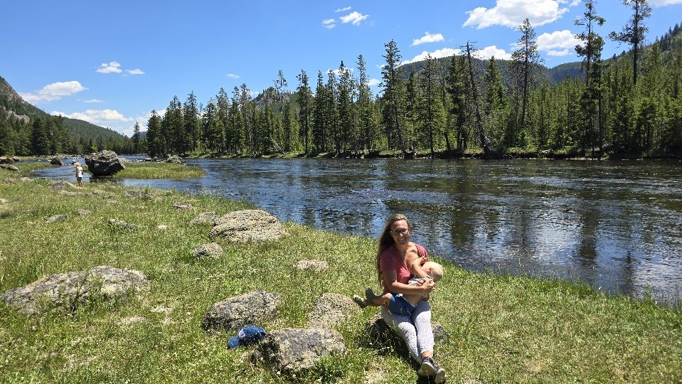Stephanie with her child by a river in the mountains
